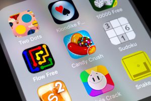 London, UK - November 9, 2016: Close-up of buttons of Candy Crush and other gaming apps on the screen of a mobile phone