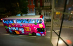 London, England - Dec 12, 2014: Captured from a window on Lower Sloane Street, one of the famous double-decker buses of London is seen, dressed fully with a pink colored Candy Crush game application advertisement of Facebook.